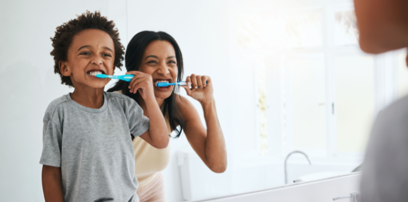 arent and child brushing teeth together promoting healthy habits at Dentistry for Children Pediatric Dental Center